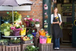 A florist standing outside of her shop holding flowers